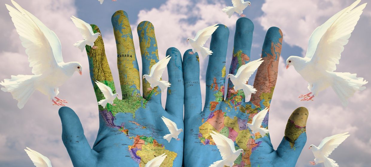 A world map painted on hands with doves