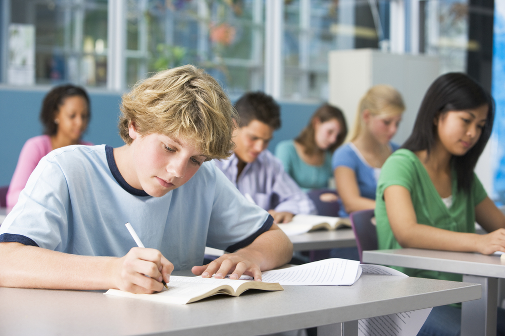 Students writing at desks. No classroom reset needed here.